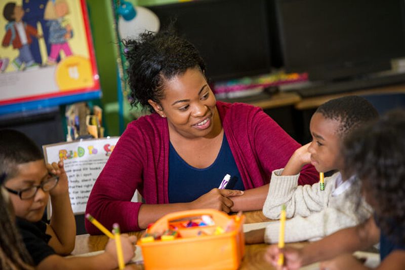 Educator mentoring a young student in a classroom