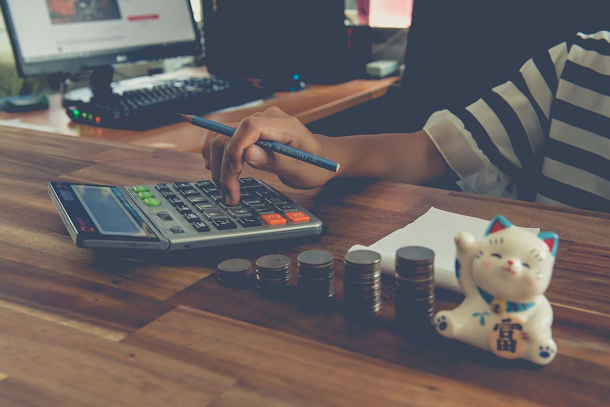 Person holding a pencil while using a calculator